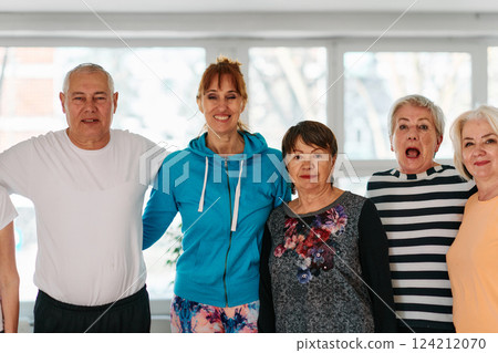 A group of seniors and one man happily pose with their yoga instructor after a successful training session. 124212070