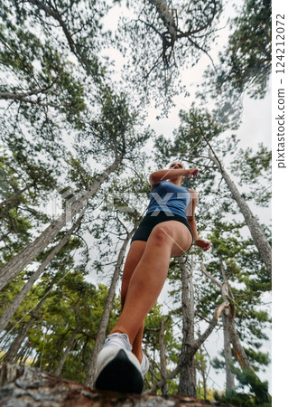Adventurous Woman Overcoming Forest Obstacles with Determination and Agility. 124212072