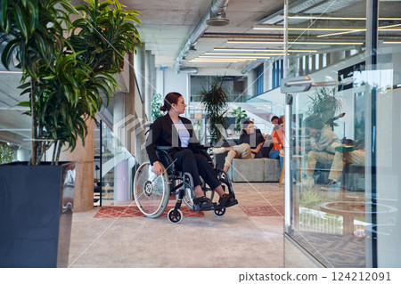 In a modern office, a young businesswoman in a wheelchair is surrounded by her supportive colleagues, embodying the spirit of inclusivity and diversity in the workplace In a modern office, a young businesswoman in a wheelchair is surrounded by her supportive colleagues, embodying the spirit of inclusivity and diversity in the workplace 124212091