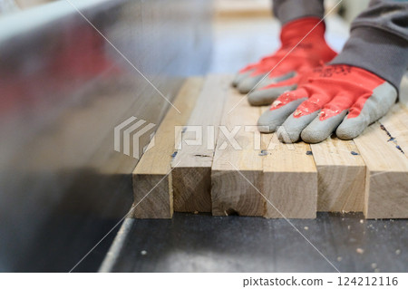 Close Up of Worker Carefully Cutting and Planing Wooden Pieces for Furniture in Wood Industry 124212116