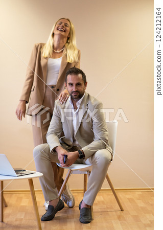 A business couple posing for a photograph together against a beige backdrop, capturing their professional partnership and creating a timeless image of unity and success. 124212164