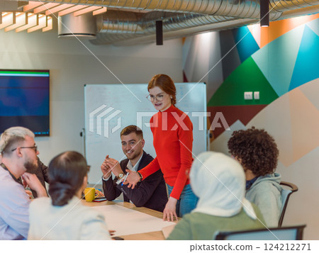 A diverse team of business experts in a modern glass office, attentively listening to a colleague's presentation, fostering collaboration and innovation 124212271