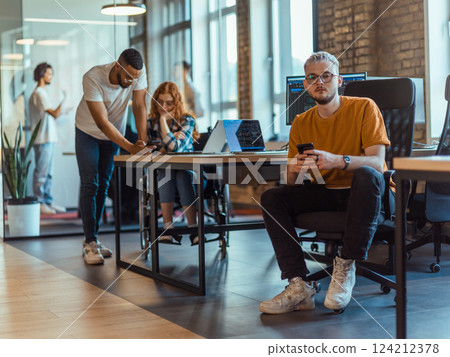 A diverse group of young business individuals congregates in a modern startup coworking center, embodying collaborative innovation and a dynamic atmosphere 124212378