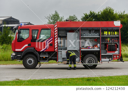 A firefighter meticulously prepares a modern firetruck for a mission to evacuate and respond to dangerous situations, showcasing the utmost dedication to safety and readiness in the face of a fire A firefighter meticulously prepares a modern firetruck for a mission to evacuate and respond to dangerous situations, showcasing the utmost dedication to safety and readiness in the face of a fire 124212430