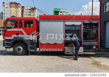 A dedicated firefighter preparing a modern firetruck for deployment to hazardous fire-stricken areas, demonstrating readiness and commitment to emergency response 124212452
