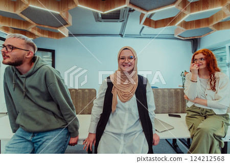 A group of young business professionals stands together, taking a well-deserved break from their busy workday, showcasing camaraderie, teamwork, and a moment of relaxation in their dynamic workplace 124212568