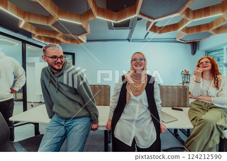 A group of young business professionals stands together, taking a well-deserved break from their busy workday, showcasing camaraderie, teamwork, and a moment of relaxation in their dynamic workplace 124212590