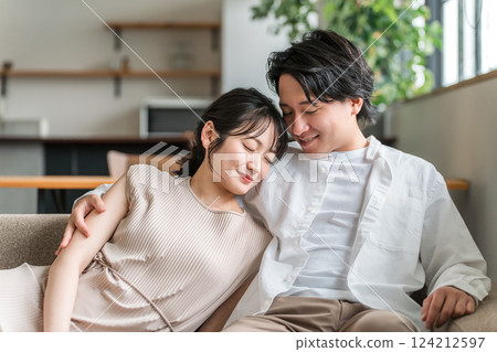 Young Asian couple sitting on sofa in living room at home 124212597