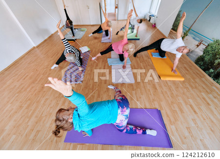 Wide Photo of Senior Women Embrace Wellness: Yoga and Stretching in a Sunlit Space 124212610