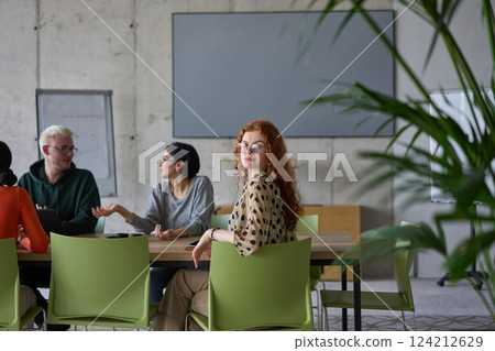 A young, diverse business team sitting together in a modern office, exchanging ideas and business plans, fostering collaboration and innovation for future success. 124212629