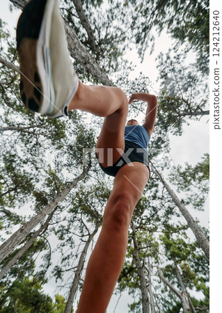 Adventurous Woman Overcoming Forest Obstacles with Determination and Agility. Adventurous Woman Overcoming Forest Obstacles with Determination and Agility. 124212640
