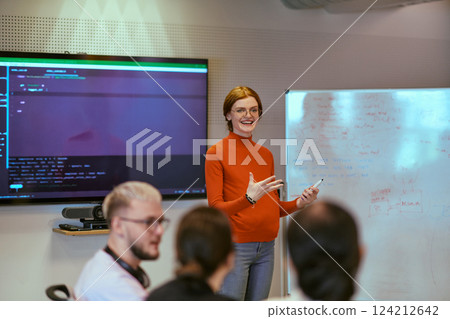 A pregnant business woman with orange hair confidently presents her business plan to colleagues in a modern glass office, embodying entrepreneurship and innovation 124212642