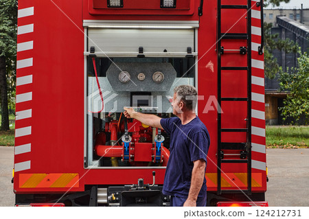 A dedicated firefighter preparing a modern firetruck for deployment to hazardous fire-stricken areas, demonstrating readiness and commitment to emergency response 124212731