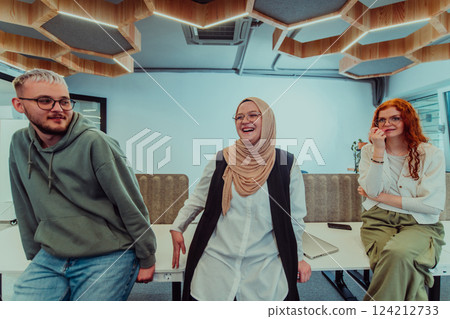 A group of young business professionals stands together, taking a well-deserved break from their busy workday, showcasing camaraderie, teamwork, and a moment of relaxation in their dynamic workplace 124212733