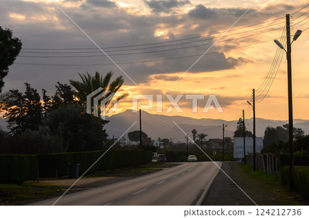 Sunset paints the horizon along a tranquil road in the countryside 124212736