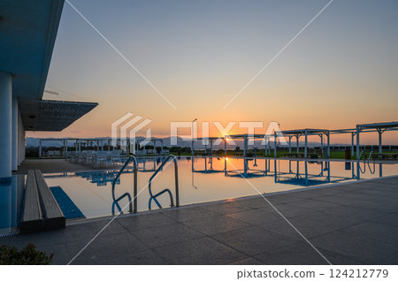 Tranquil sunset reflecting on a serene poolside retreat by the mountains 124212779