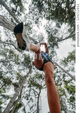 Adventurous Woman Overcoming Forest Obstacles with Determination and Agility. 124212812