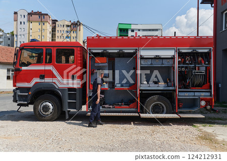 A dedicated firefighter preparing a modern firetruck for deployment to hazardous fire-stricken areas, demonstrating readiness and commitment to emergency response 124212931