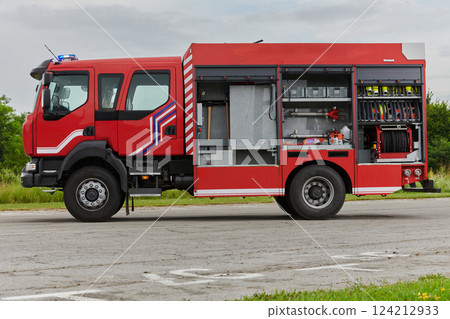 In this captivating scene, a state-of-the-art firetruck, equipped with advanced rescue technology, stands ready with its skilled firefighting team, prepared to intervene and respond rapidly to 124212933