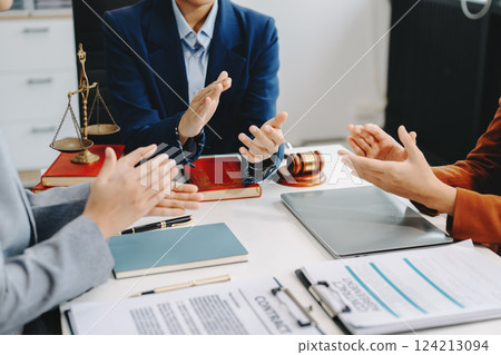 Two lawyers are discussing about contract paper, law matters determination, pointing.law and hammer on the table 124213094