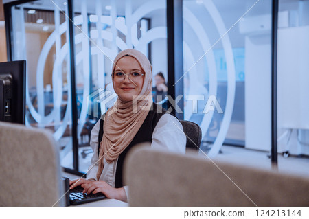 In a modern office, a young Muslim entrepreneur wearing a hijab sits confidently and diligently works on her computer, embodying determination, creativity, and empowerment in the business world In a modern office, a young Muslim entrepreneur wearing a hijab sits confidently and diligently works on her computer, embodying determination, creativity, and empowerment in the business world 124213144