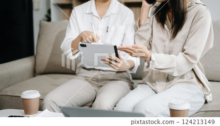 Two Asian businesswoman discuss investment project working and planning strategy with tablet laptop computer on sofa Two Asian businesswoman discuss investment project working and planning strategy with tablet laptop computer on sofa 124213149