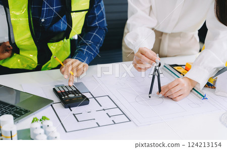 Creative architect projecting on the big drawings with architectural project at construction site at desk in office 124213154
