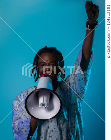In a powerful and symbolic image, an African American man wears traditional clothing, passionately wields a megaphone against a striking blue background, with his hand raised in the air symbolizing In a powerful and symbolic image, an African American man wears traditional clothing, passionately wields a megaphone against a striking blue background, with his hand raised in the air symbolizing 124213181