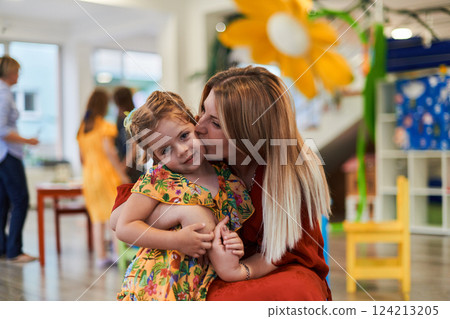 A cute little girl kissing and hugs her mother in preschool 124213205