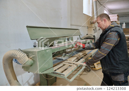 Close Up of Worker Carefully Cutting and Planing Wooden Pieces for Furniture in Wood Industry 124213308