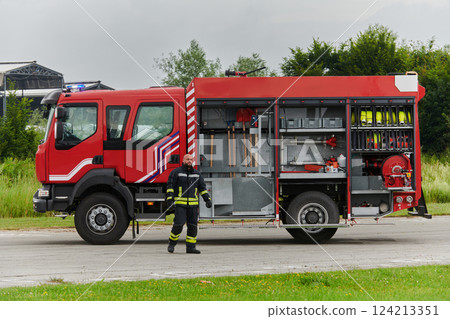 A firefighter meticulously prepares a modern firetruck for a mission to evacuate and respond to dangerous situations, showcasing the utmost dedication to safety and readiness in the face of a fire A firefighter meticulously prepares a modern firetruck for a mission to evacuate and respond to dangerous situations, showcasing the utmost dedication to safety and readiness in the face of a fire 124213351