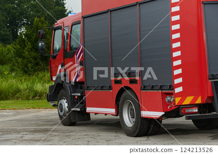 In this captivating scene, a state-of-the-art firetruck, equipped with advanced rescue technology, stands ready with its skilled firefighting team, prepared to intervene and respond rapidly to 124213526