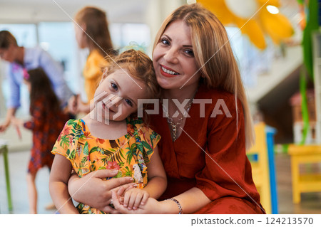 A cute little girl kissing and hugs her mother in preschool 124213570