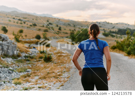 Determined Female Athlete Stretching After an Intense Run Through Rugged Mountain Terrain. 124213578