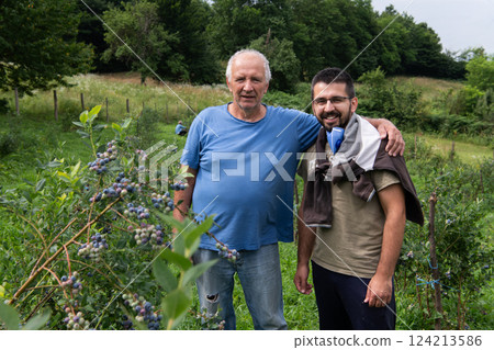Father and Son Farmers Inspecting the Quality of Their Blueberry Harvest Together. 124213586