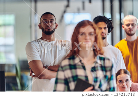 A diverse group of business people walking a corridor in the glass-enclosed office of a modern startup, including a person in a wheelchair and a woman wearing a hijab, showing a dynamic mix of 124213718