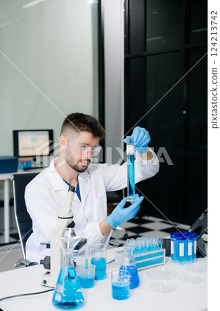male scientist working with micro pipettes analyzing biochemical samples, advanced science 124213742