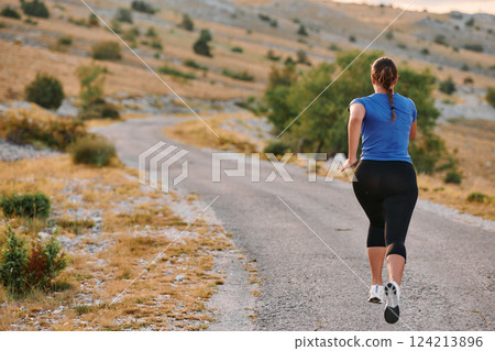 Empowered Runner Embracing Nature's Beauty on a Serene Morning Trail. 124213896