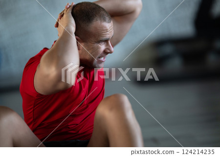 A muscular man performing crunches in the gym, focusing on building core strength and achieving his fitness goals A muscular man performing crunches in the gym, focusing on building core strength and achieving his fitness goals 124214235