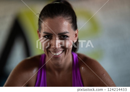 A fit and determined woman takes a short break during an intense workout session at the gym, showcasing strength and perseverance. A fit and determined woman takes a short break during an intense workout session at the gym, showcasing strength and perseverance. 124214433