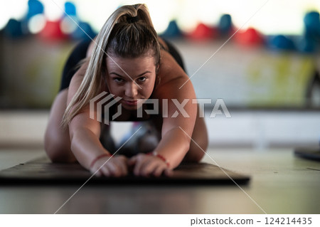 A woman stretches her body in the gym after an intense workout, a healthy muscle stretch after training. 124214435
