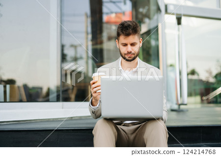 Handsome unshaven businessman walking with laptop, tablet and smartphone on city Handsome unshaven businessman walking with laptop, tablet and smartphone on city 124214768