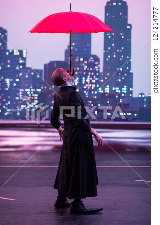 Mysterious Clown Performer with Red Umbrella in Urban Nightscape. 124214777