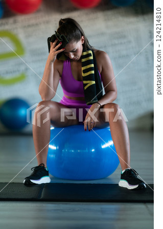 A fit woman takes a well deserved break in the gym, sipping water from her bottle after an intense workout session 124214810