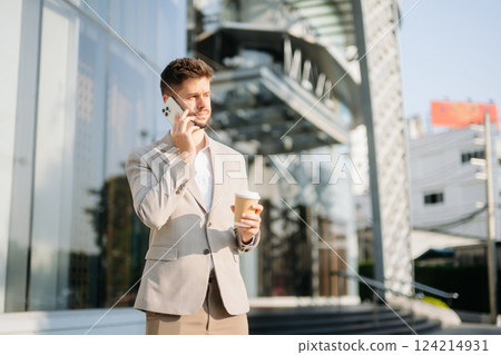 Handsome unshaven businessman walking with laptop, tablet and smartphone on city Handsome unshaven businessman walking with laptop, tablet and smartphone on city 124214931