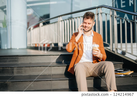 Successful businessman works outdoors near the office holds a tablet 124214967