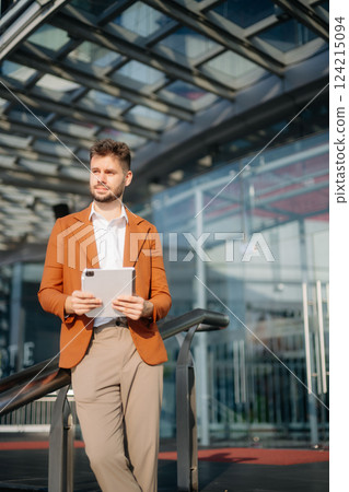 Successful businessman works outdoors near the office holds a tablet Successful businessman works outdoors near the office holds a tablet 124215094