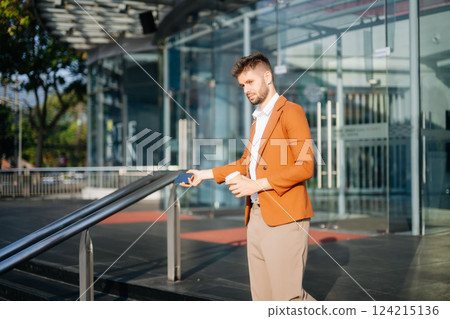 Successful businessman works outdoors near the office holds a tablet Successful businessman works outdoors near the office holds a tablet 124215136