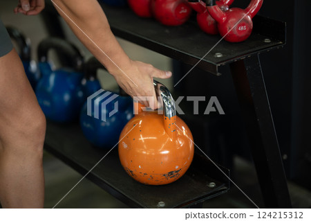 A close up shot of a man gripping dumbbells, ready to push through his intense workout in the gym, displaying focus, strength, and determination 124215312