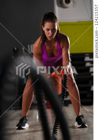 Fit Woman Performing Rope Conditioning Exercise in the Gym 124215357